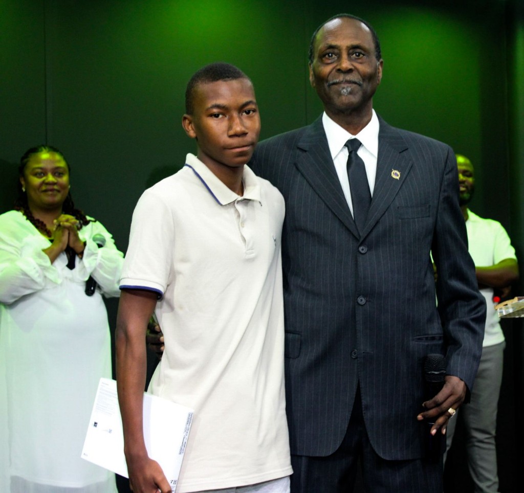 Young man with a mentor’s arm around his shoulder after receiving a tablet